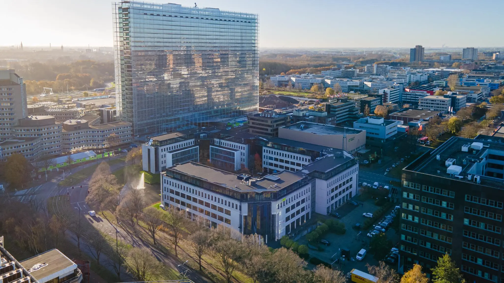Luchtfoto van de De Bruyn Kopsstraat in Den Haag met moderne kantoorgebouwen en een hoog glazen pand op de achtergrond.
